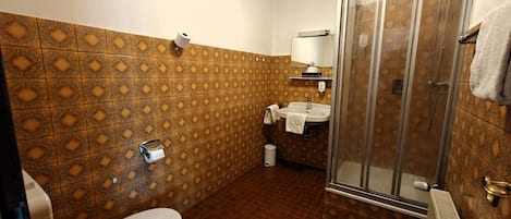 Un baño con azulejos estampados, un inodoro, un lavamanos y una ducha.