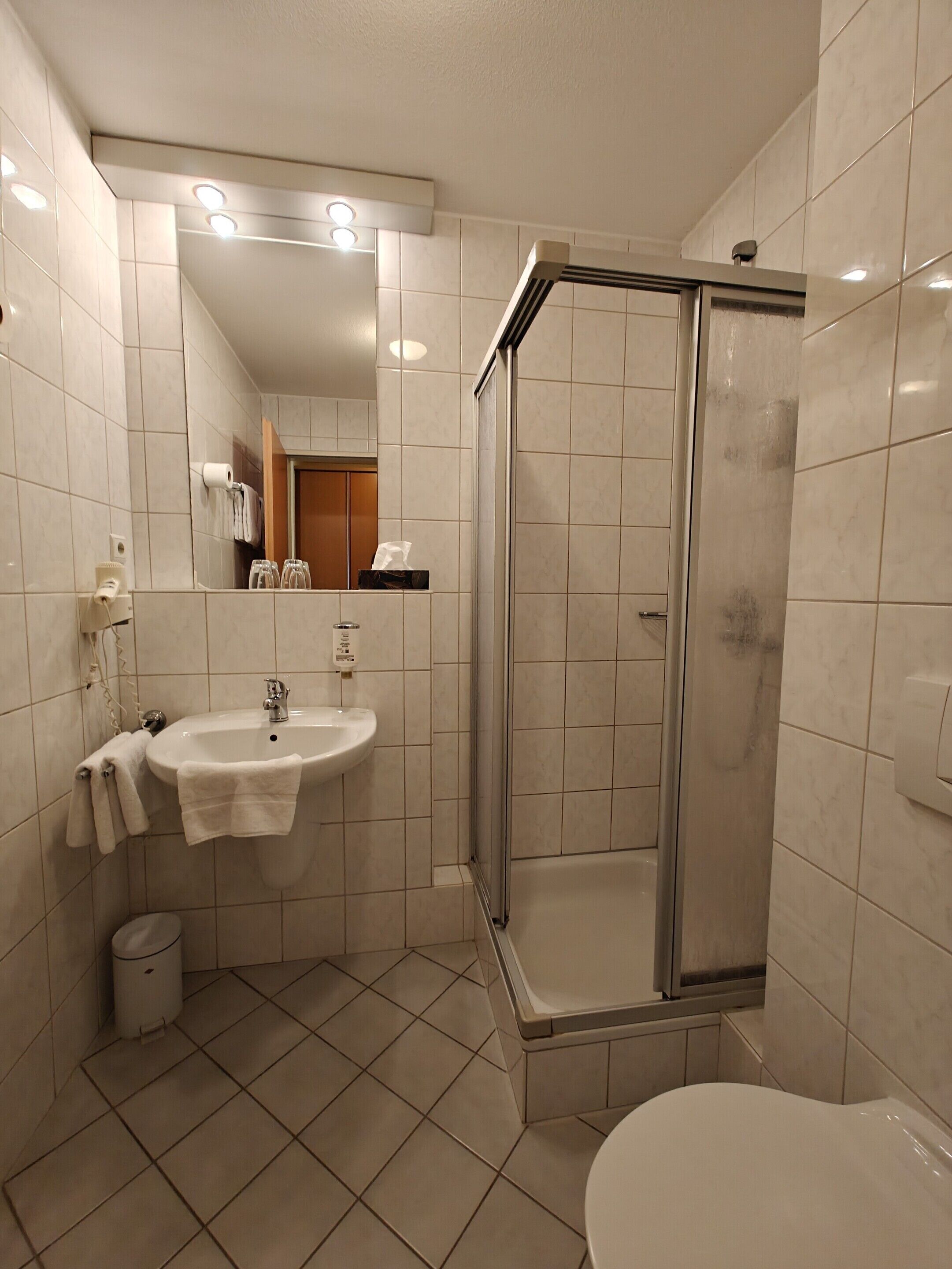 Een moderne badkamer met een wastafel, spiegel en douche.