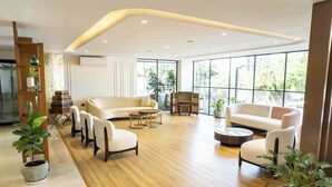 A modern living room with a sofa, chairs, a coffee table, and potted plants. - Trunk & Trolley A Luxury Boutique Hotel  (Hyderabad)