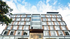 A multi-story hotel with a modern design, featuring a large glass entrance and a flat roof with solar panels. - Trunk & Trolley A Luxury Boutique Hotel  (Hyderabad)