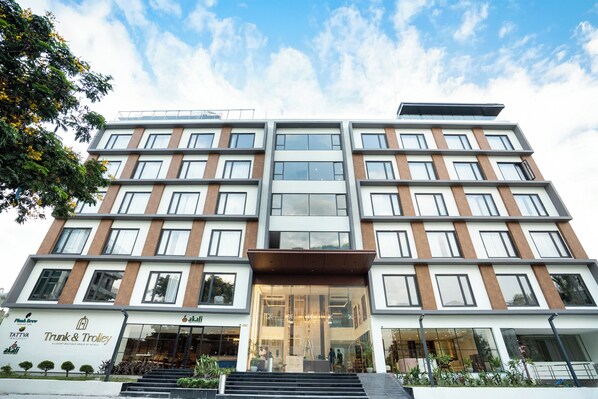 A multi-story hotel with a modern design, featuring a large glass entrance and a flat roof with solar panels.
