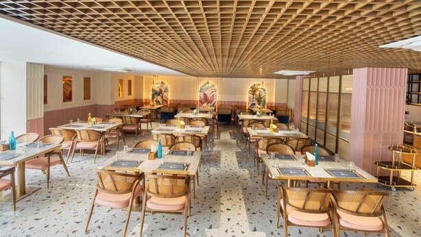 A spacious dining area with multiple tables and chairs, a patterned ceiling, and a terrazzo floor. - Trunk & Trolley A Luxury Boutique Hotel  (Hyderabad)
