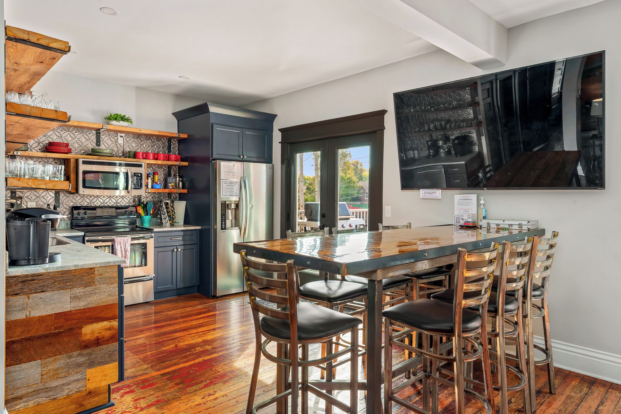 Una cocina moderna con una isla central, taburetes de bar y un amplio ventanal.
