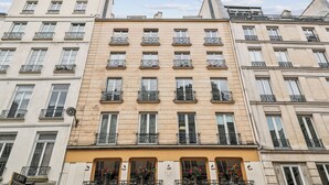 A multi-story building with balconies, large windows, and a sign indicating a cafe. - Magnificent apartment II - 1BR/4P - Opéra-Bourse (Paris)