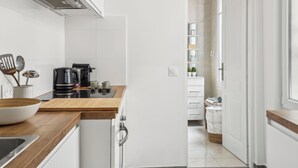 A modern kitchen with white cabinets, a wooden countertop, and a coffee maker. - Magnificent apartment II - 1BR/4P - Opéra-Bourse (Paris)