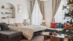 A modern living room with a sofa, a coffee table, and a bed with patterned bedding. - Magnificent apartment II - 1BR/4P - Opéra-Bourse (Paris)