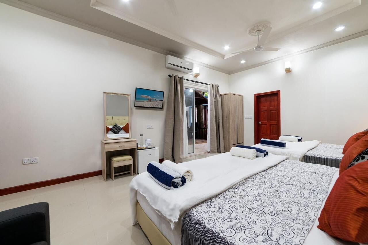 A hotel room with a bed, a desk, a chair, a wardrobe, and an air conditioning unit.
