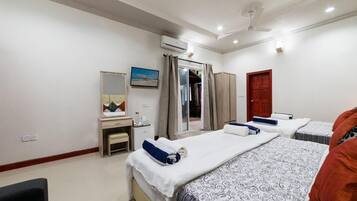 A hotel room with a bed, a desk, a chair, a wardrobe, and an air conditioning unit.