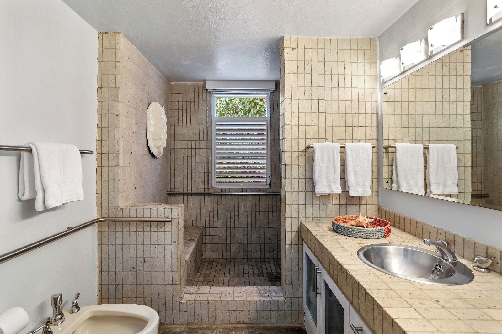 A compact bathroom with a toilet, sink, and window with blinds.