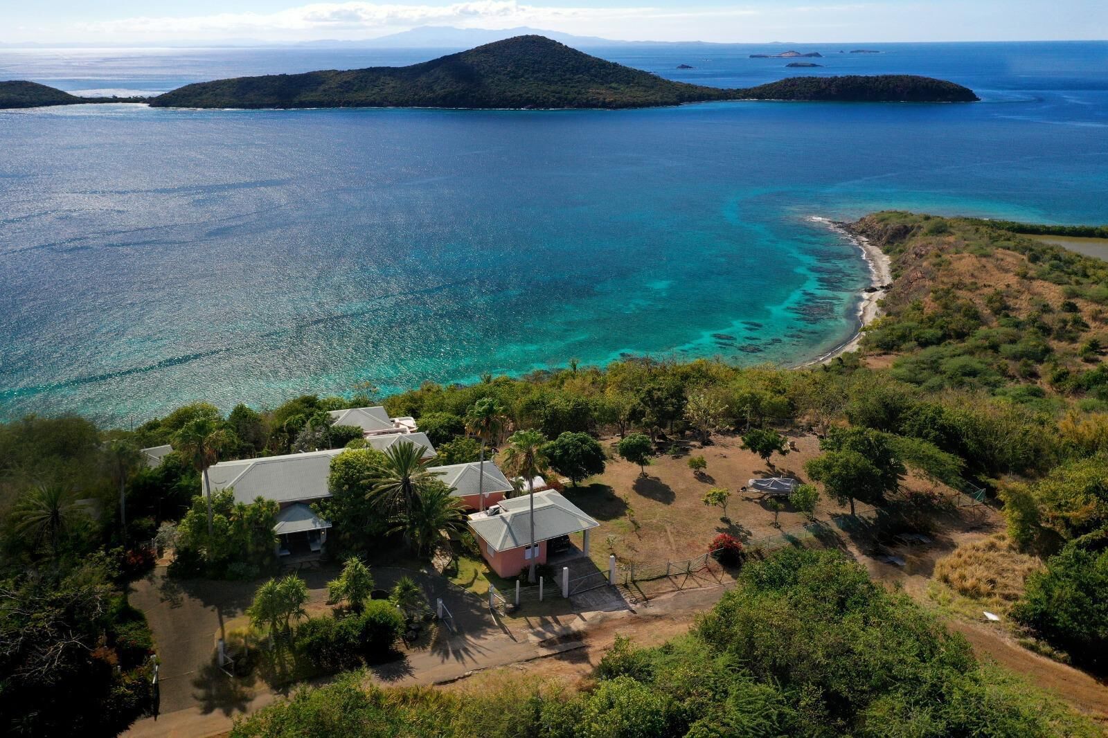 A coastal property with a paved driveway, a small building, and a beach.