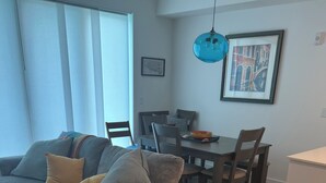 Un salon moderne avec un canapé gris, une table à manger et un coin cuisine.