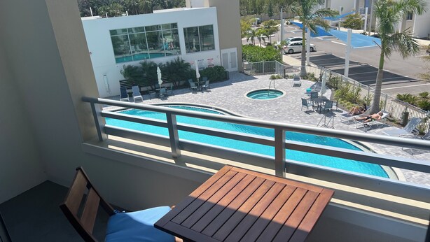 Un balcon avec une piscine, des chaises longues et une table.