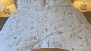 A bed with a floral print bedspread, a wooden headboard, and two bedside lamps on a nightstand.