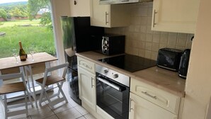 A compact kitchen with a dining area, featuring a built-in oven, a stovetop, and a toaster.