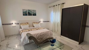 A bedroom with a bed, bedside tables, a wardrobe, a glass coffee table, and a ceiling light fixture. - ROOM WITH INDOOR WELLNESS (Dakar)
