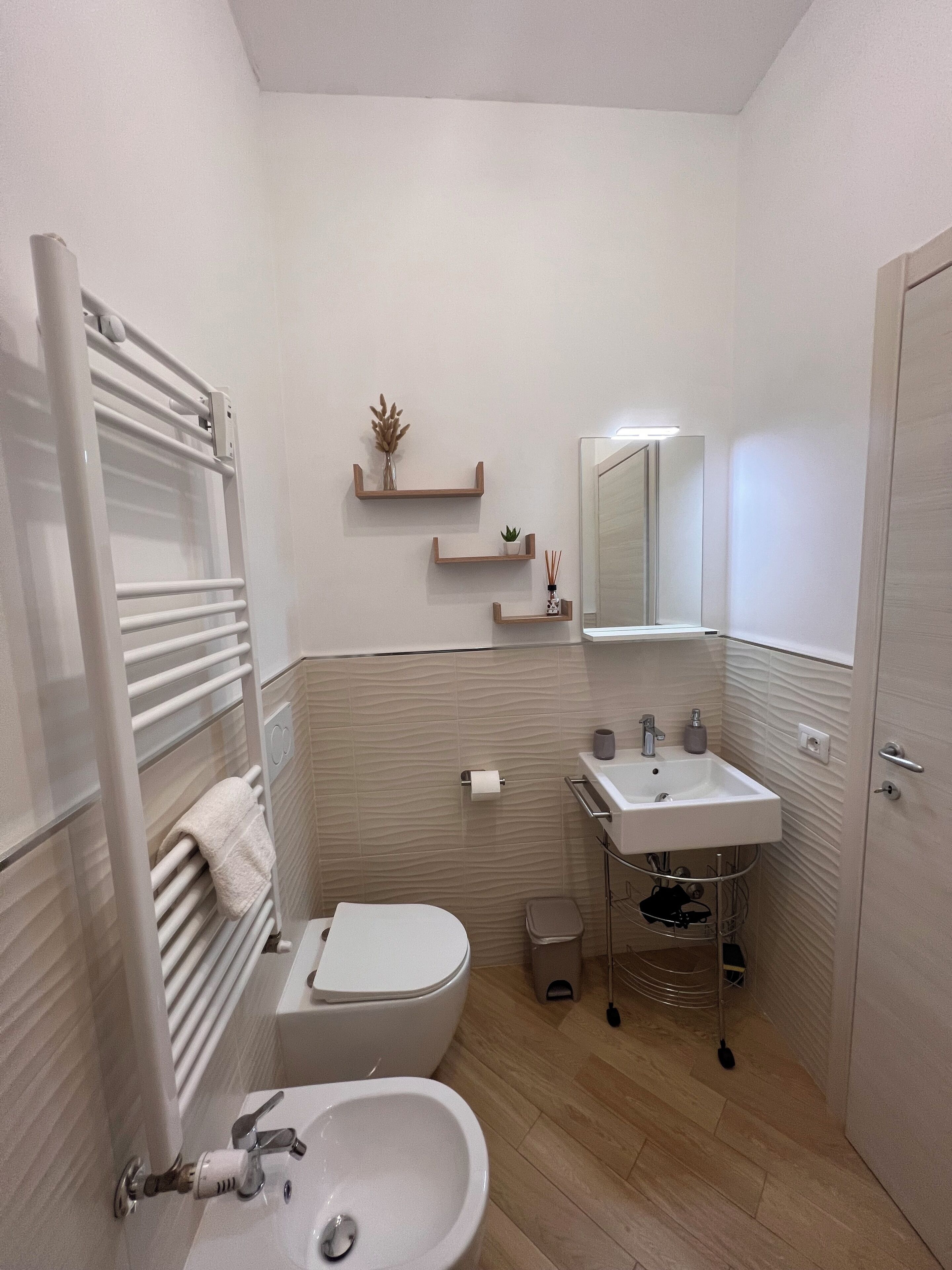 Un baño moderno con inodoro, lavamanos y perchero para toallas.
