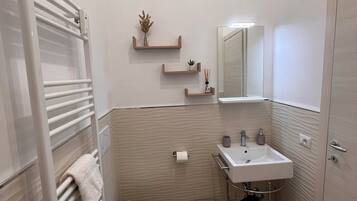 Een moderne badkamer met toilet, wastafel en handdoekhouder.