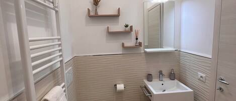 Un baño moderno con inodoro, lavamanos y perchero para toallas.