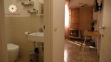 A modern bathroom with a toilet, sink, and shelves. There is a wooden cabinet with a mirror and a plant.