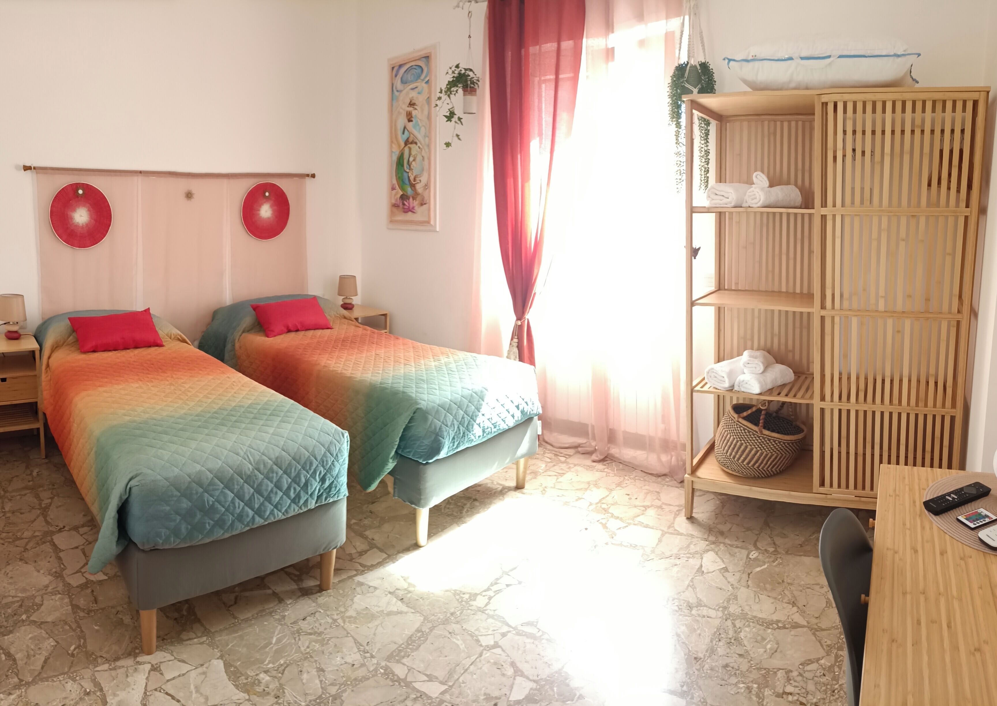 Ein Zimmer mit zwei Betten, einem Holzbodenregal mit Handtüchern, einem Tisch mit einer Fernbedienung und einem Fliesenboden.