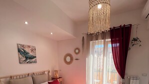 A bedroom with a large bed, a chandelier, a window with curtains, and a radiator.