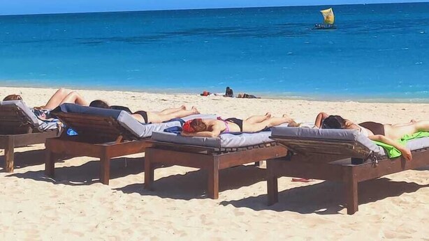 Una playa con sillones de madera y un cielo azul despejado.