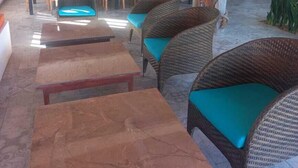 Un amplio espacio al aire libre con mobiliario de mimbre y mesas de madera.