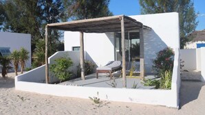 Un área de descanso al aire libre moderna con una pérgola de madera, una única silla lounge y una mesita.