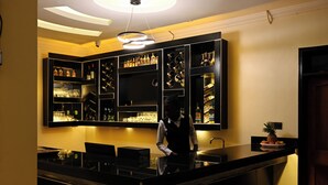 A bar area with a counter, shelves with bottles, and a ceiling light fixture. - Neon Hotel Ntinda (Kampala)