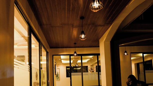 A hallway with a wooden ceiling and a tiled floor, leading to a room with a glass door. - Neon Hotel Ntinda (Kampala)