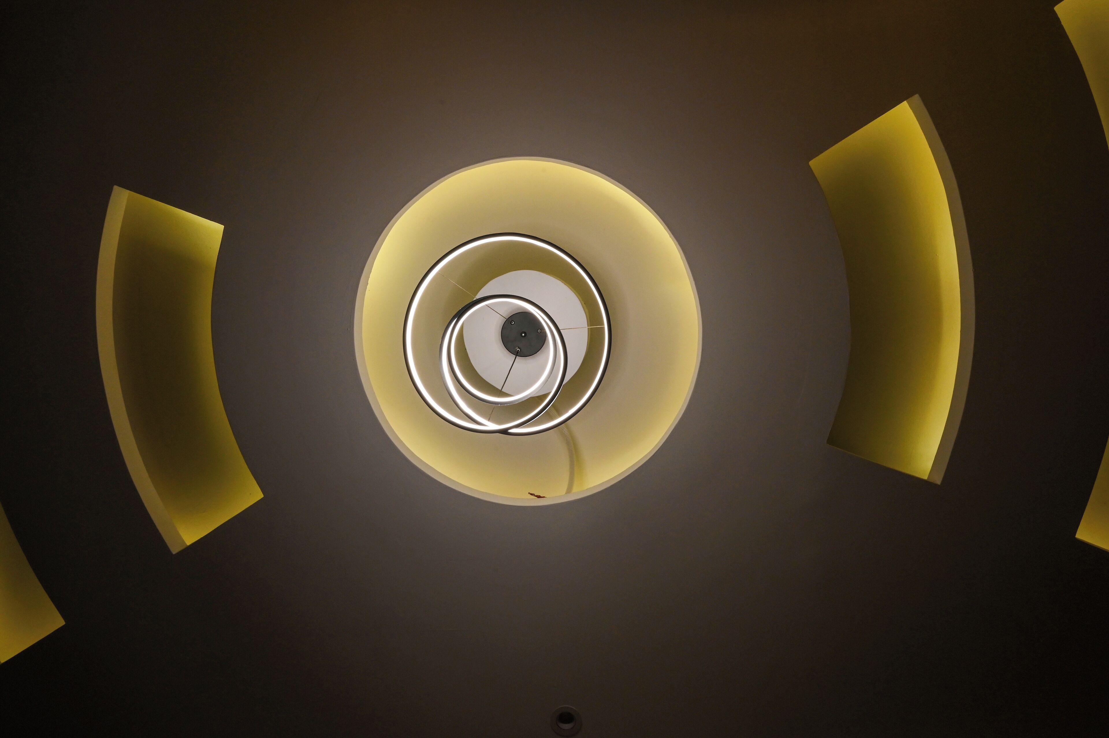 A spiral staircase with a central light fixture and a circular design.