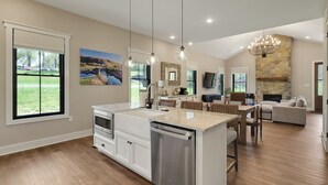 Een ruime keuken met een groot eiland, houten vloeren en een stenen openhaard.