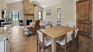 Amplia sala de estar con mesa de comedor de madera, chimenea de piedra y un candelabro moderno.