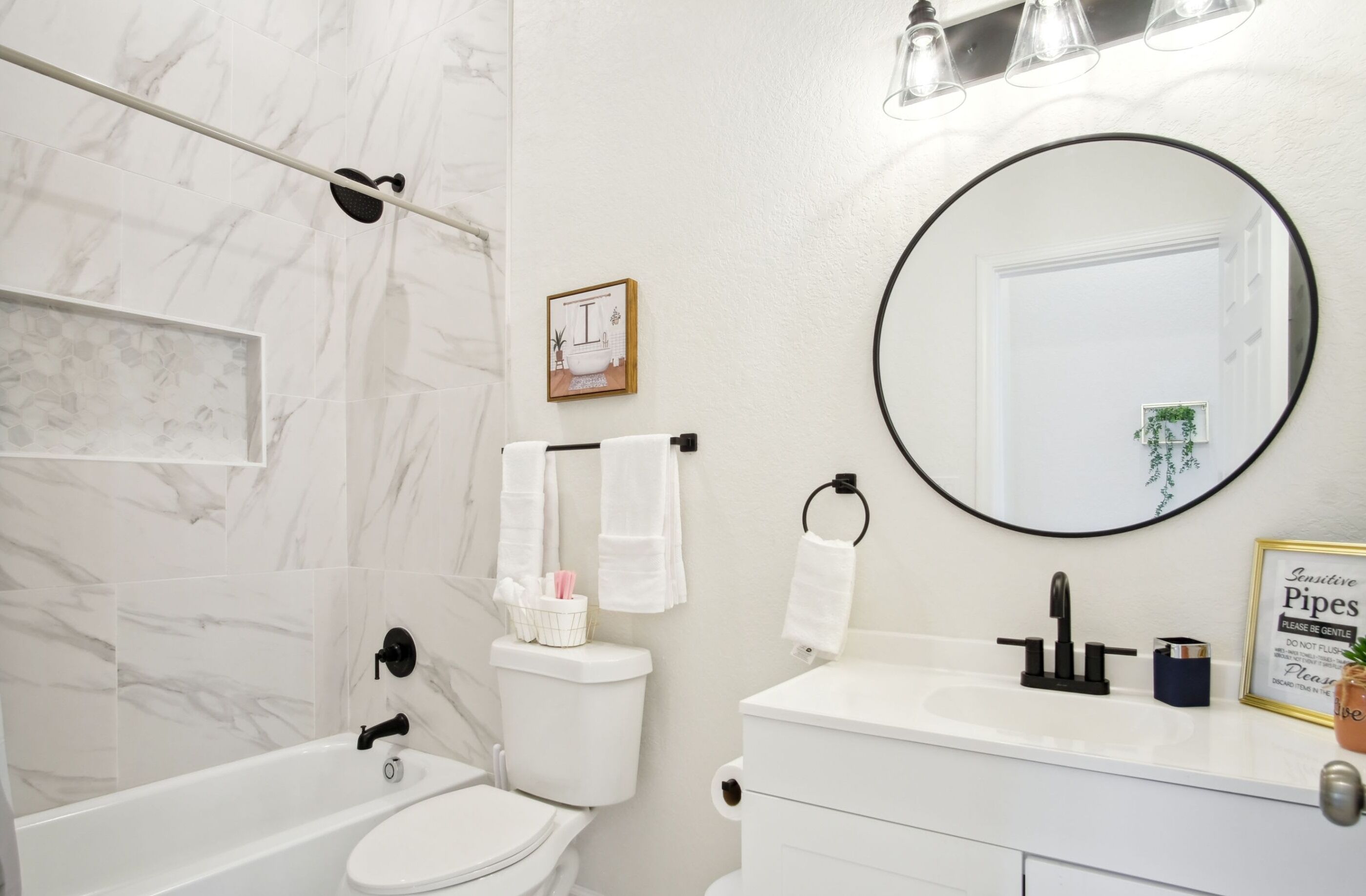 Un baño con bañera, inodoro, lavabo y un espejo grande.