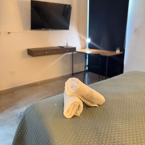 Relax in comfort with a neatly made bed, flat-screen TV, and desk workspace.