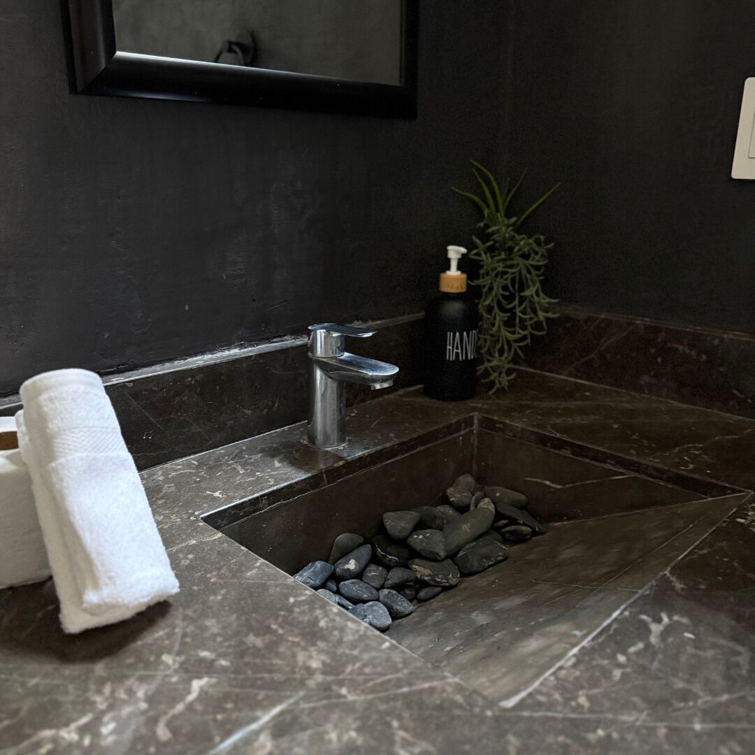 A bathroom with a black sink, a mirror, and a bottle of hand soap.