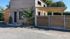 A two-story house with a brick exterior, a wooden front door, and a covered patio area.