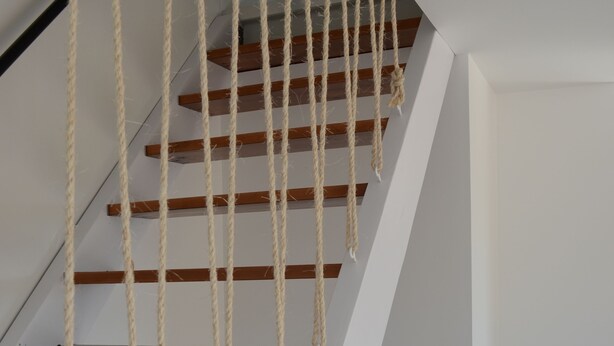 A staircase with wooden steps and rope handrails.