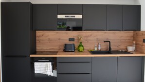 A modern kitchen with dark cabinetry, a wooden countertop, a built-in oven, and a sink.