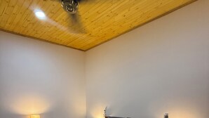 A bedroom with a wooden ceiling, a large bed with a wooden frame, two bedside tables with lamps, and a ceiling fan.