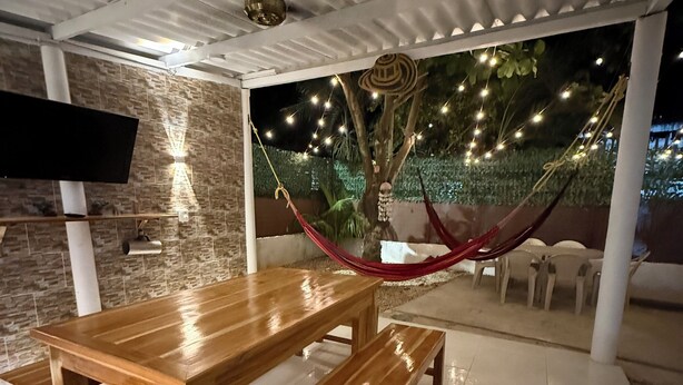A wooden dining table with benches, a hammock, and a TV mounted on a wall.