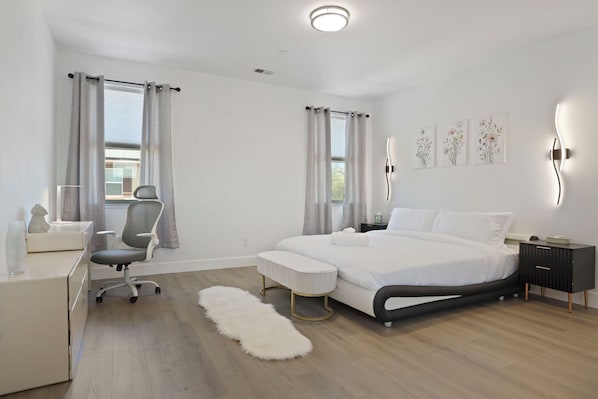 Un dormitorio moderno con una cama grande, un escritorio, una silla y una alfombra mullida.