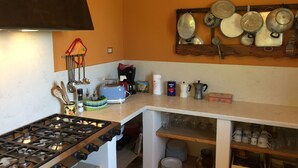 Een keuken met een gasfornuis, een broodrooster en diverse keukengerei en apparaten.