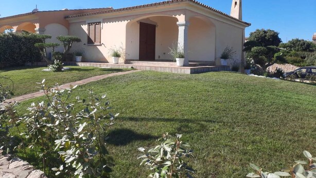 A two-story house with a tiled roof, a central entrance with a door, and a small bell tower. - Nala House - Villa 800 mt from the sea (Budoni)