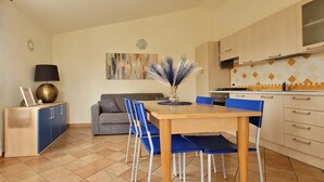 A compact kitchen with a dining table, chairs, a sofa, and a cabinet. - Nala House - Villa 800 mt from the sea (Budoni)