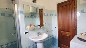A bathroom with a shower, sink, mirror, and wooden door. - Nala House - Villa 800 mt from the sea (Budoni)