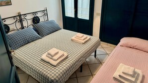 A bedroom with a bed, two pillows, a bedside table, and a window with curtains. - Aeolian Villa - Apartment with two bedrooms, sea view, and garden (Lipari)