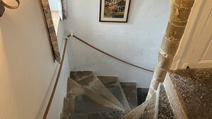 A stone staircase with a handrail, a framed picture on the wall, and a light fixture on the left. - Ferme fortifiée d Enguenard (Formigny La Bataille)