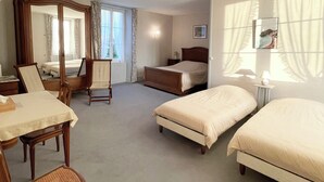 A hotel room with a large bed, a smaller bed, a desk with a chair, a wardrobe, and a large mirror. - Ferme fortifiée d Enguenard (Formigny La Bataille)