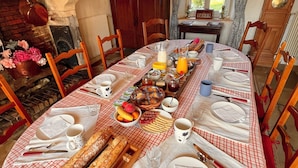A dining table set with a checkered tablecloth, various dishes, bread, and utensils. - Ferme fortifiée d Enguenard (Formigny La Bataille)